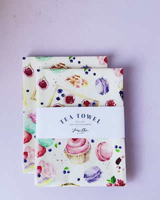Video showing Jean Choe's cotton canvas tea towel with vibrant watercolor desserts: cupcakes, tarts, macarons