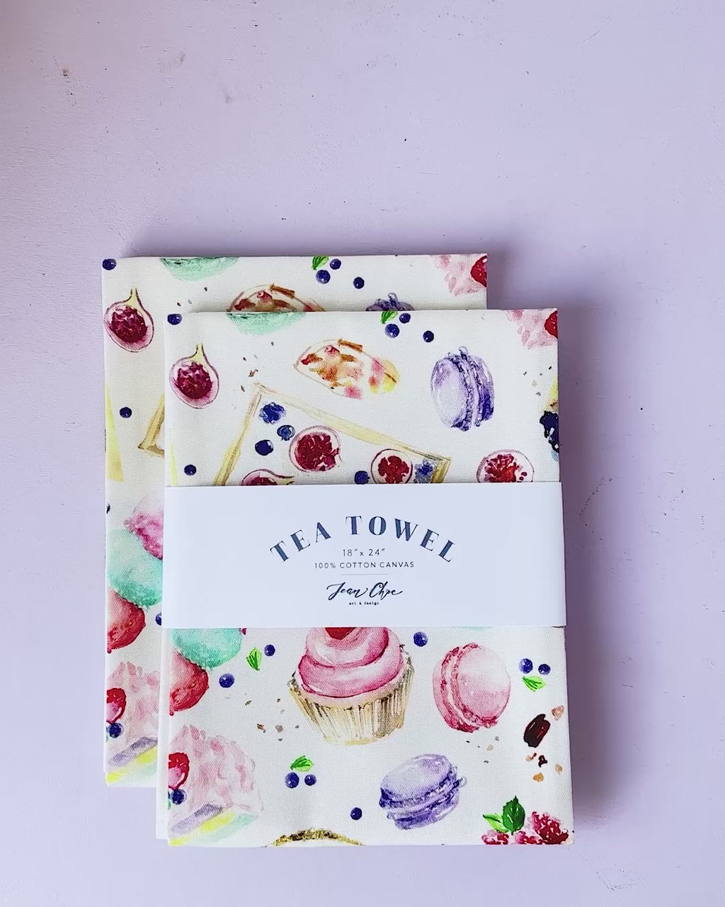 Video showing Jean Choe's cotton canvas tea towel with vibrant watercolor desserts: cupcakes, tarts, macarons